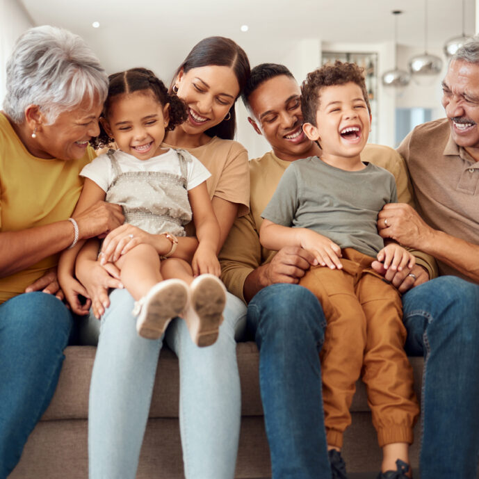 Happy, big family and quality time bonding of children, parents and grandparents together on a sofa. Laughing kids having fun with mom, dad and grandparent on a home living room couch with happiness