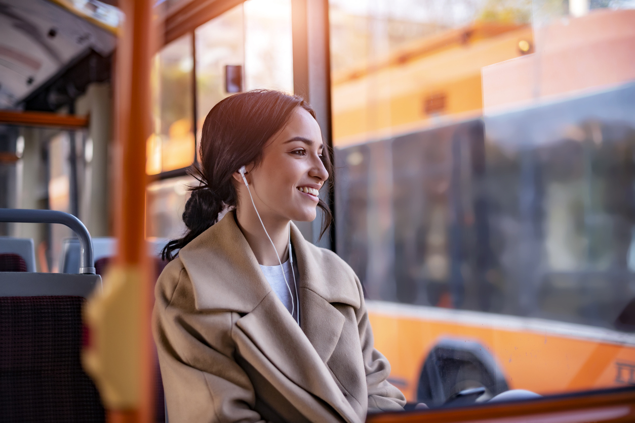 Woman on bus listening to music and smiling