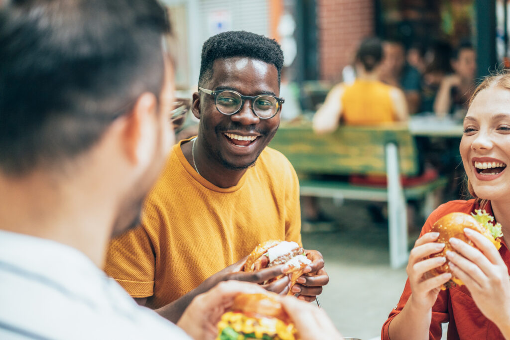 Friends eating burgers and have fun in outdoor restaurant